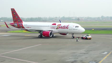 tow-truck-at-airport,-pushing-airplane-to-runway