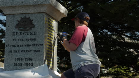 Artista-De-Restauración-Femenina-Repara-Las-Letras-Pintadas-En-Un-Monumento-Conmemorativo-De-La-Guerra-Mundial