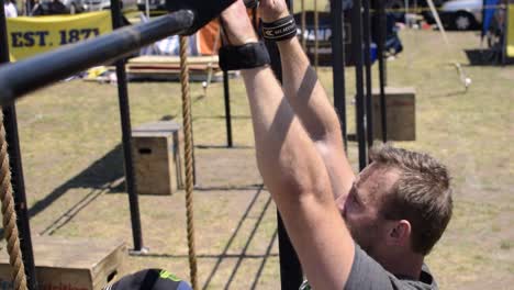 Un-Hombre-Atlético-Se-Cuelga-De-Una-Barra-Y-Realiza-Levantamientos-De-Piernas-Durante-Una-Competencia-De-Ajuste-Cruzado,-Un-Gran-Entrenamiento-Abdominal-Y-Central