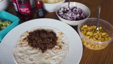 Schwenk--Und-Kippansicht-Von-Gemahlenem-Taco-Fleisch,-Das-Auf-Einem-Tortillabrot-Liegt