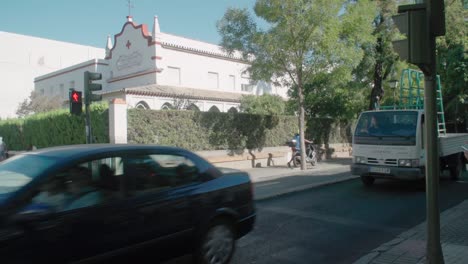 Ambulance,-cars,-bike,-and-motorcycle-drive-past-Red-Cross-building-in-Spain