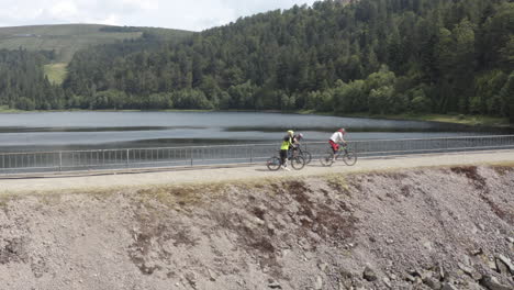 Three-mountain-biker-starting-on-the-dam-wall-of-lac-d'altenweiher-in-the-french-vosges