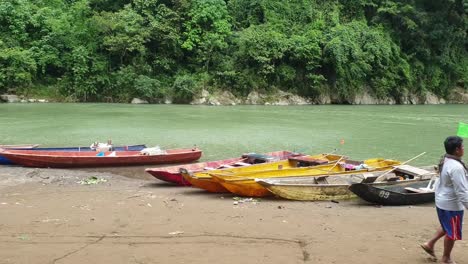 Boatman-walking-pass-several-boats-docked-on-the-riverside,-Rural-life