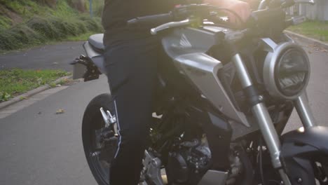 Close-up-of-a-motorcyclist-which-is-sitting-down-on-his-motorcylce-with-sunset-in-the-background