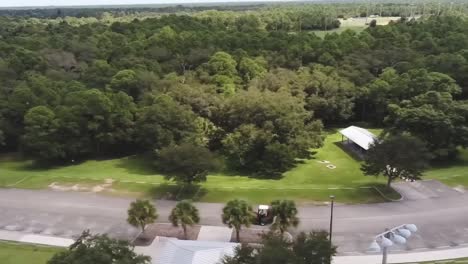 Overheard-view-of-park-maintenance-equipment-moving-down-the-road,-with-trees-in-the-background