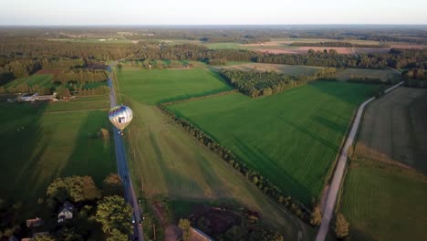 Largas-Sombras-Se-Extienden-Sobre-Las-Exuberantes-Tierras-De-Cultivo-De-Valmiera,-Letonia,-Mientras-Un-Globo-Aerostático-Se-Desplaza-Silenciosamente-A-Lo-Largo