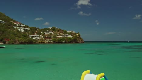 Un-Par-De-Vueltas-De-Natación-A-Través-Del-Océano-En-La-Playa-De-Morne-Rouge-Con-Un-Castillo-Hinchable-En-Primer-Plano