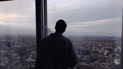 Silueta-De-Un-Turista-Adulto-Mirando-Por-El-Cristal-De-La-Ventana-Al-Horizonte-De-Londres-Por-La-Noche