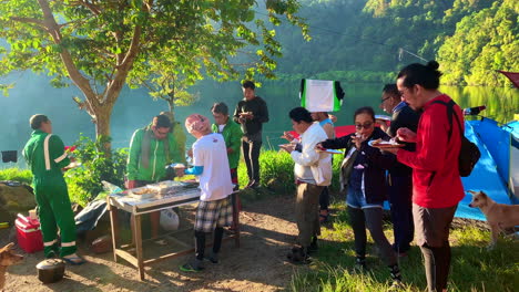 14-Sekunden-Filmmaterial-Mit-Menschen,-Die-Im-Freien-Bei-Hellem-Tageslicht-Essen,-Mit-Einem-See-Im-Hintergrund