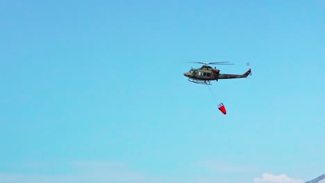 Military-helicopter-fighting-fire-with-a-water-bucket