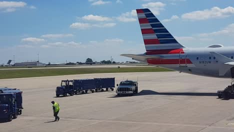 Marshaller-Geht-Zum-Gepäckwagen,-Im-Hintergrund-Startende-Flugzeuge,-Flughafen-Dallas,-Texas