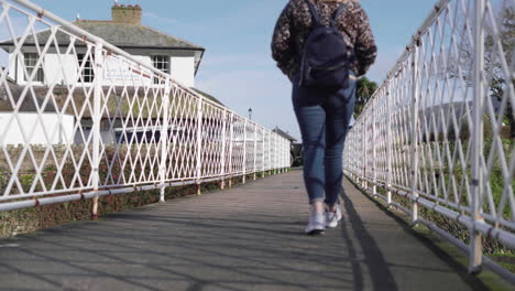 Mujer-Con-Mochila-Caminando-Por-Un-Puente-De-Metal,-ángulo-Bajo