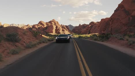 Ferrari-Negro-Con-Un-Rolls-Royce-Blanco-Conduciendo-En-El-Valle-Del-Fuego,-Nevada,-Estados-Unidos