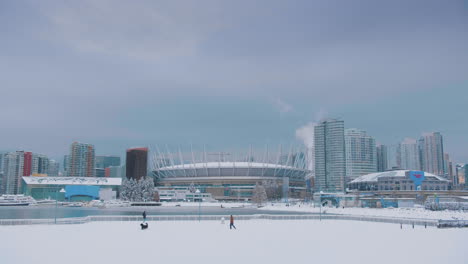 Verschneite-Skyline-Der-Innenstadt-Von-Vancouver-Mit-Spielendem-Hund-Und-Mann