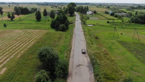 Vista-Aérea-De-Los-Coches-En-Una-Carretera-Antigua-Con-Baches-Cerca-De-Las-Tierras-De-Cultivo