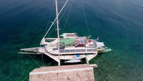 Velero-Trimarán-Bigkanu-En-Una-Cabaña-De-Buceo-En-Arrecifes-Oceánicos,-Círculo-Aéreo-Alrededor-Del-Tiro