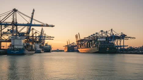 Zeitraffer-Moderner-Containerschiffe,-Die-Bei-Sonnenuntergang-In-Einem-Hamburger-Seehafen-An-Der-Elbe-Be--Und-Entladen-Werden