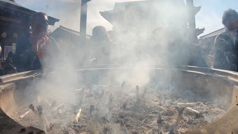 Close-up-wide-angle-view-of-japanese-people-worshipping-in-the-smoke-of-an-incense-pot-in-Asakusa,-Tokyo