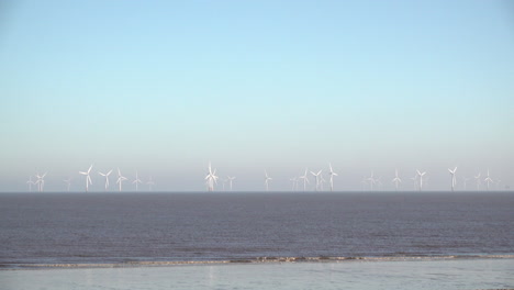 Eine-Familie-Mit-Kinderwagen-Und-Hunden-Spaziert-Am-Strand-In-Der-Nähe-Von-Ingoldmells-Vor-Dem-Riesigen-Windpark-Lincs-Entlang,-Der-Acht-Kilometer-Vor-Der-Küste-In-Der-Nordsee-Vor-Der-Ostküste-Englands-Liegt