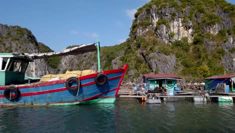 Floating-fish-farm-village-with-boats-fastened-on-the-docks-seen-in-profile,-Dolly-left-shot