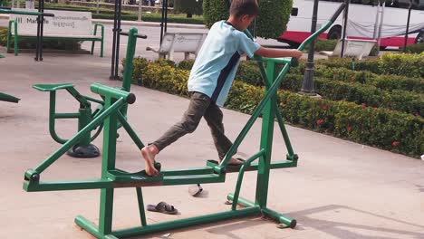 Toma-En-Cámara-Lenta-De-Un-Niño-Usando-Una-Máquina-De-Ejercicio-En-El-Parque