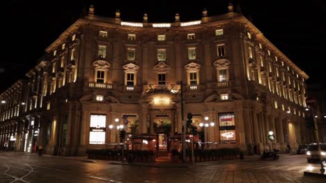 Night-timelapse-of-Starbucks-coffee-store-in-Milan-from-the-street-with-cars-and-tramway-passing-by,-still-wide-shot