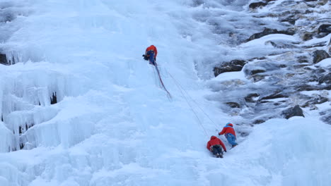 Un-Equipo-De-Escaladores-De-Hielo-Preparando-Cuerdas-A-Lo-Largo-De-Una-Enorme-Pared-De-Hielo