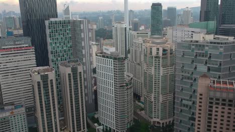 Establishing-and-revealing-aerial-view-of-downtown-and-city-centre-with-kuala-lumpur-tower-menara-and-sunset-in-the-background-in-Malaysia