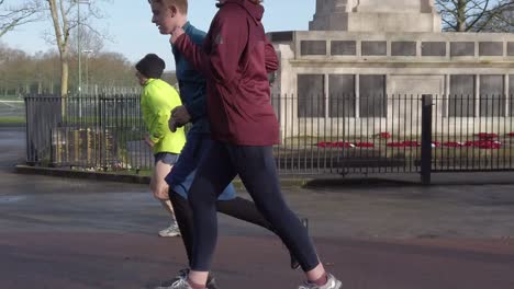 Active-fitness-group-jogging---walking-in-wet-rainy-park-in-slow-motion-side-on-runners-passing