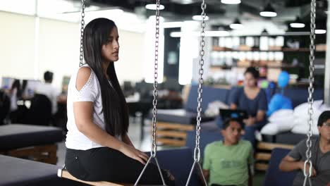 Millennial-employees-at-a-trendy-startup-company-watch-a-presentation-siting-on-comfortable-furniture-and-swings