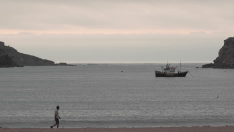 Man-Walking-By-The-Beach-Of-Sao-Martinho-do-Porto-Portugal---wide-shot-slow-motion