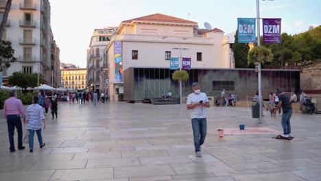 People-Strolling-Around-Infront-Of-Ancient-Roman-Theatre-In-Malaga-City,-Spain-On-An-Early-Morning---panning-shot