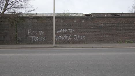 Los-Autos-Pasan-Frente-A-Un-Grafiti-Antigubernamental-En-Una-Pared-De-Ladrillos.