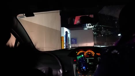 Interior-Hatchback-Noche-Primer-Plano-2-Adultos-Se-Reúnen-En-La-Nueva-Normalidad-Del-Bloqueo-De-Covid-19-Con-Un-Drive-Thru-Compartiendo-Una-Botella-De-Gel-Desinfectante-Para-Manos-Después-De-Aceptar-Un-Pedido-Por-Lavado-De-Autos-2-2