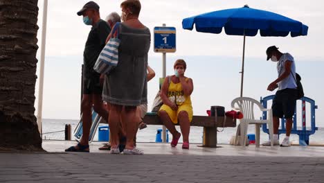 Gesperrte-Aufnahme-Von-Menschen,-Die-Während-Der-Covid-19-Pandemie-Am-Strand-Schlange-Standen,-Um-Ein-Paket-Zu-Holen