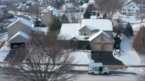 US-Mail-carrier-delivers-Christmas-package-gift-to-home-covered-in-winter-holiday-snow