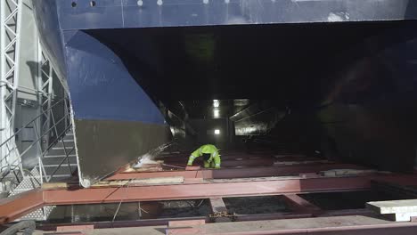 Trabajador-Portuario-Con-Una-Pistola-De-Chorro-De-Agua-Lavando-Un-Barco-Grande