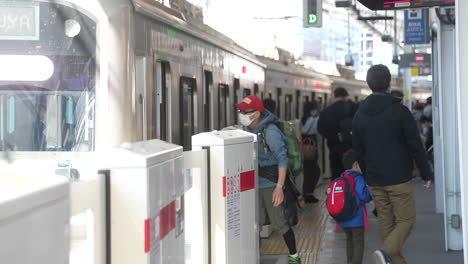 Vater-Und-Sohn-Mit-Rucksack-Steigen-Während-Der-Covid-19-Pandemie-In-Tokio,-Japan,-Aus-Dem-Zug-Und-Steigen-Am-Bahnhof-Aus