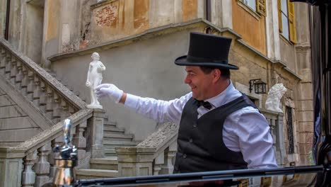 Couple-Waving-From-Balcony-At-Statenberg-Castle-To-Chauffer-Polishing-Bonnet