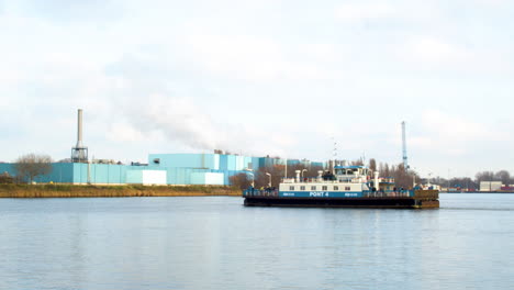 Amsterdam-ferry-crossing-river-with-a-smoking-industrial-building-in-the-background