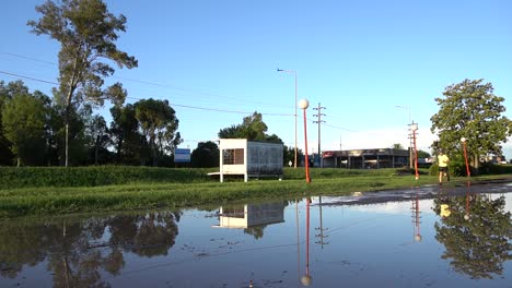 Un-Hombre-Corre-Por-Una-Vía-De-Servicio-Inundada-En-Una-Tarde-Soleada