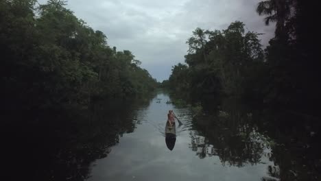 Levantando-La-Vista-De-Un-Dron-De-Un-Indígena-Remando-En-Una-Canoa-En-Un-Río-De-La-Selva-Tropical