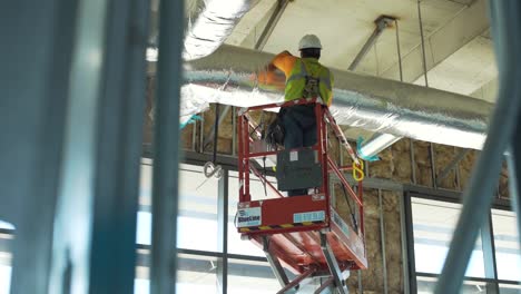 Pan-of-a-construction-worker-on-a-man-lift