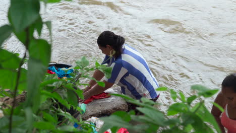 Eine-Frau-Wäscht-Und-Spült-Ihre-Kleidung,-Während-Sie-In-Einem-Fluss-Steht