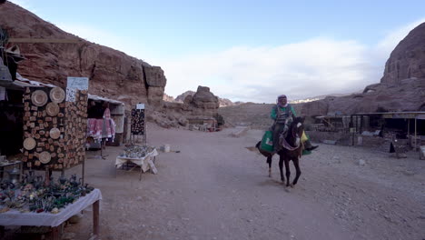 El-Niño-Camina-Por-Una-Carretera-Mientras-El-Jinete-Monta-En-Una-Mula-Pasando-Por-Tiendas-De-Vendedores-En-La-Antigua-Ciudad-De-Petra