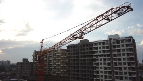 A-Crane-Panned-Across-at-a-Construction-Site-during-a-Cloudy-Evening-with-Residential-Complexes-and-Traffic-on-Street