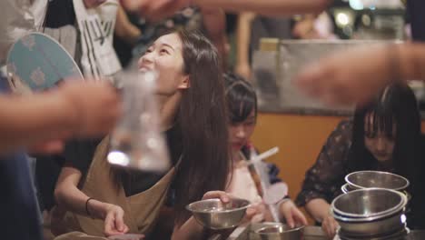 Tourists-Having-Fun-Scooping-Kingyo-Sukui-Goldfish-During-Yoiyama-Festival-At-The-Gion-Matsuri-Festival-Night-In-Kyoto,-Japan---close-up-slowmo