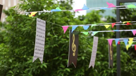 Pan-tilt-down-shot-of-colorful-small-flags-and-music-symbols-hanging-on-street