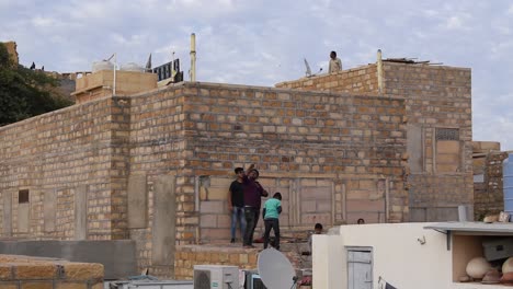 Kleine-Gruppe-Von-Jungen,-Die-Drachen-Steigen-Lassen-Und-Am-Rand-Einer-Mauer-Auf-Der-Terrasse-Stehen