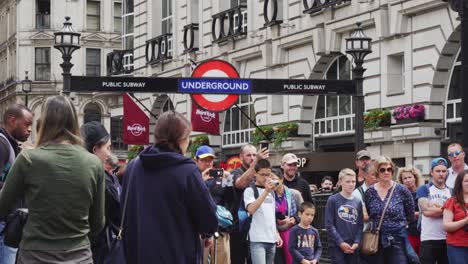 Multitud-De-Personas-Escuchando-Y-Viendo-Espectáculos-Callejeros---Busking-Bajo-El-Cartel-Subterráneo-En-Londres